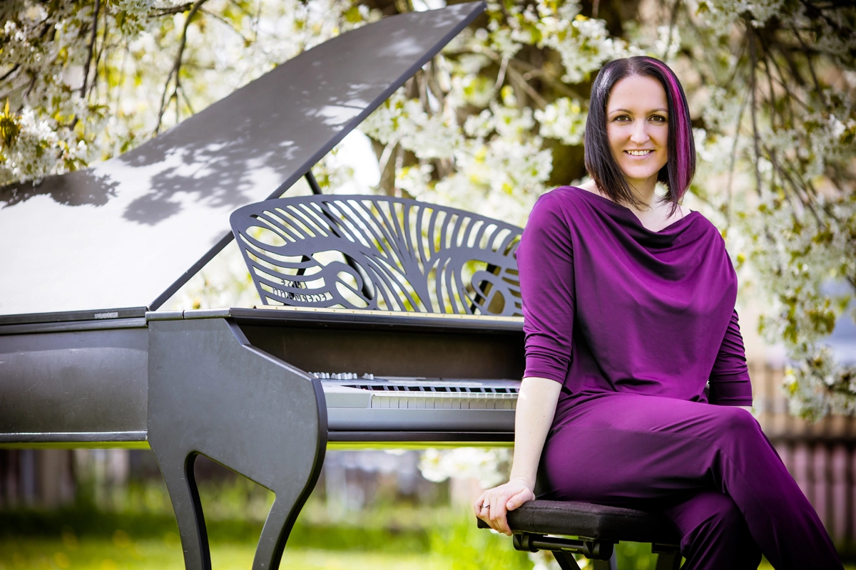 Luise Egermann sitzt am Piano unter einem Kirschbaum